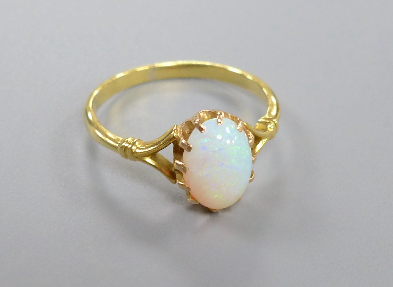 A yellow metal and cabochon oval white opal set dress ring, size O, gross 2.7 grams.
